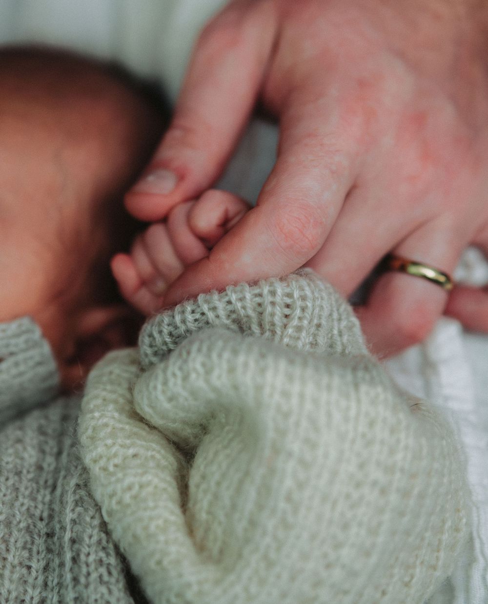 Close-up details of hands touching a knitted white fabric texture.