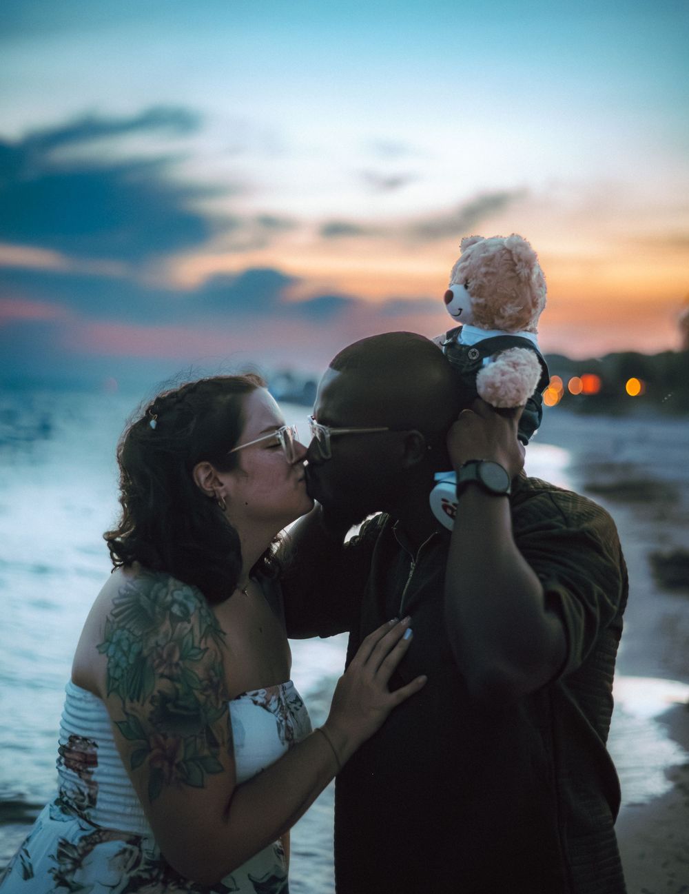 Silhouetted couple shares romantic kisses against a vibrant sunset sky.