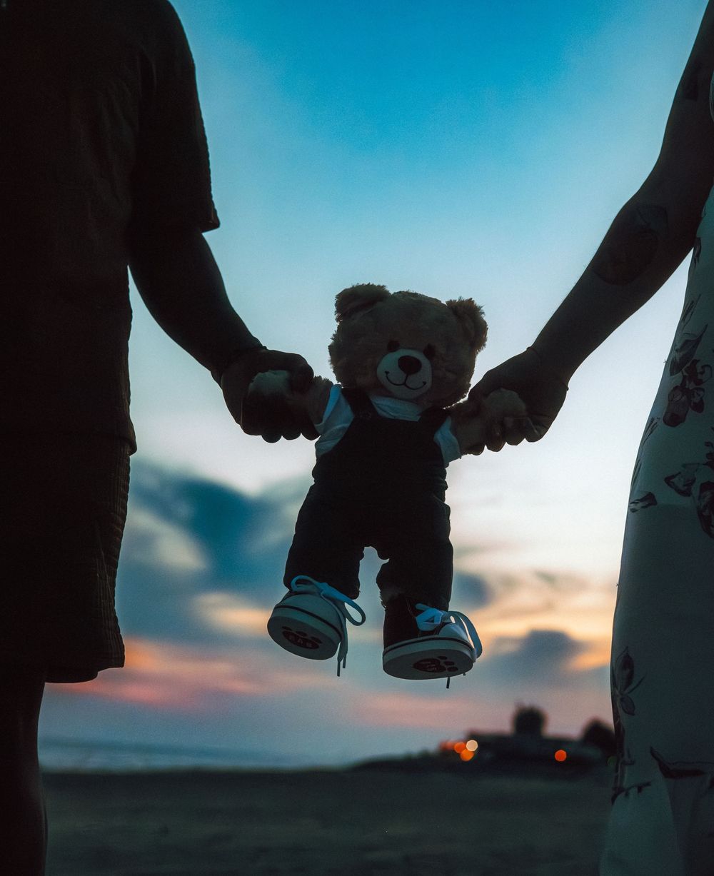 Silhouettes of baby shoes held up against a sunset sky during a pregnancy announcement.