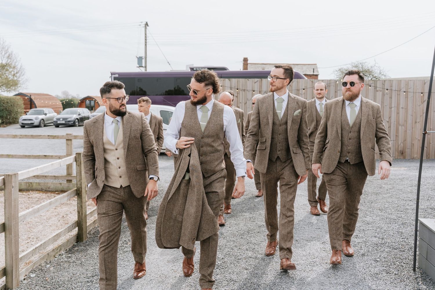 Groomsmen walking in tan suits during a wedding celebration.