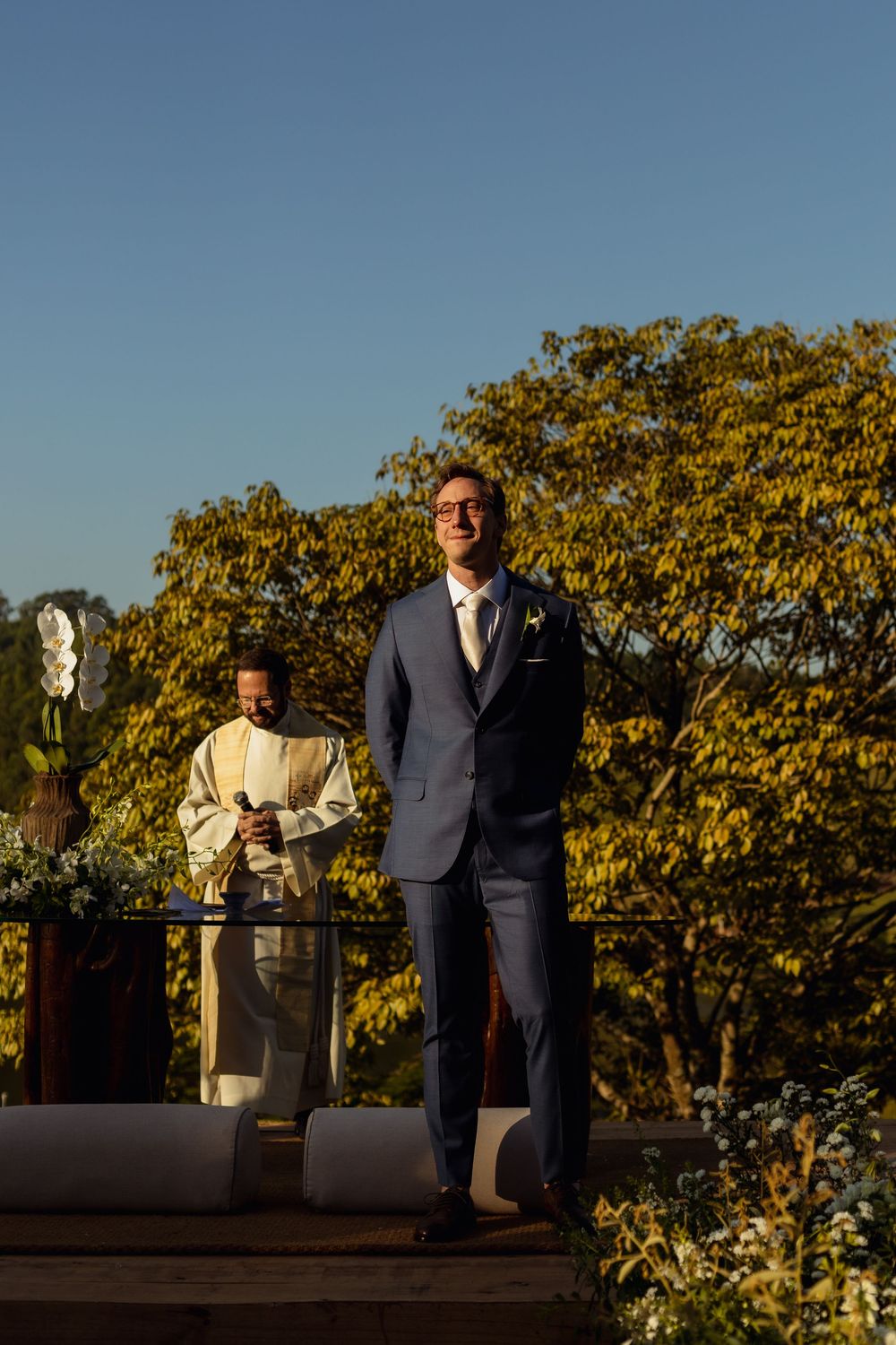 A sunny outdoor wedding ceremony with golden trees in the background.