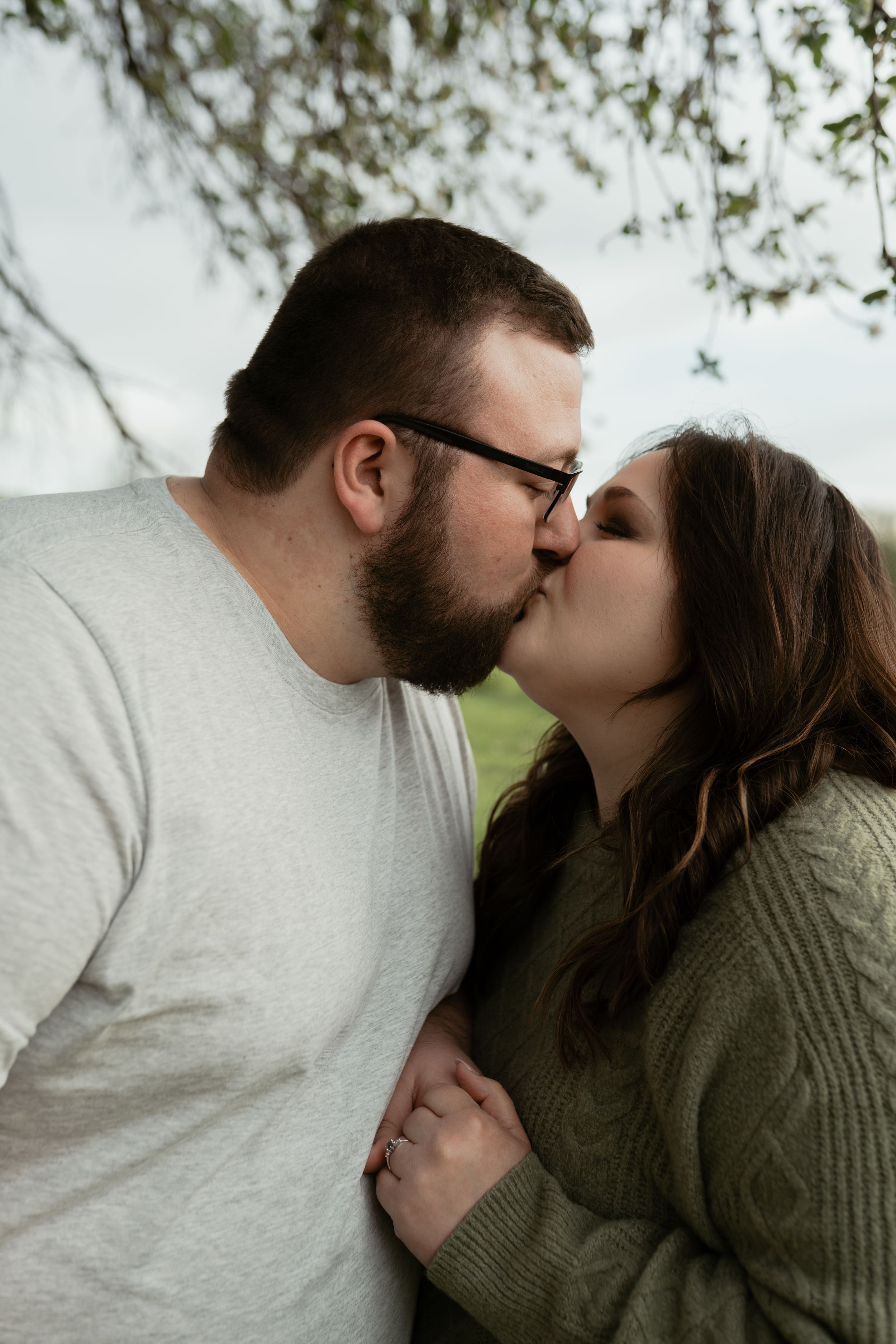 A tender moment shared between two people under tree branches.