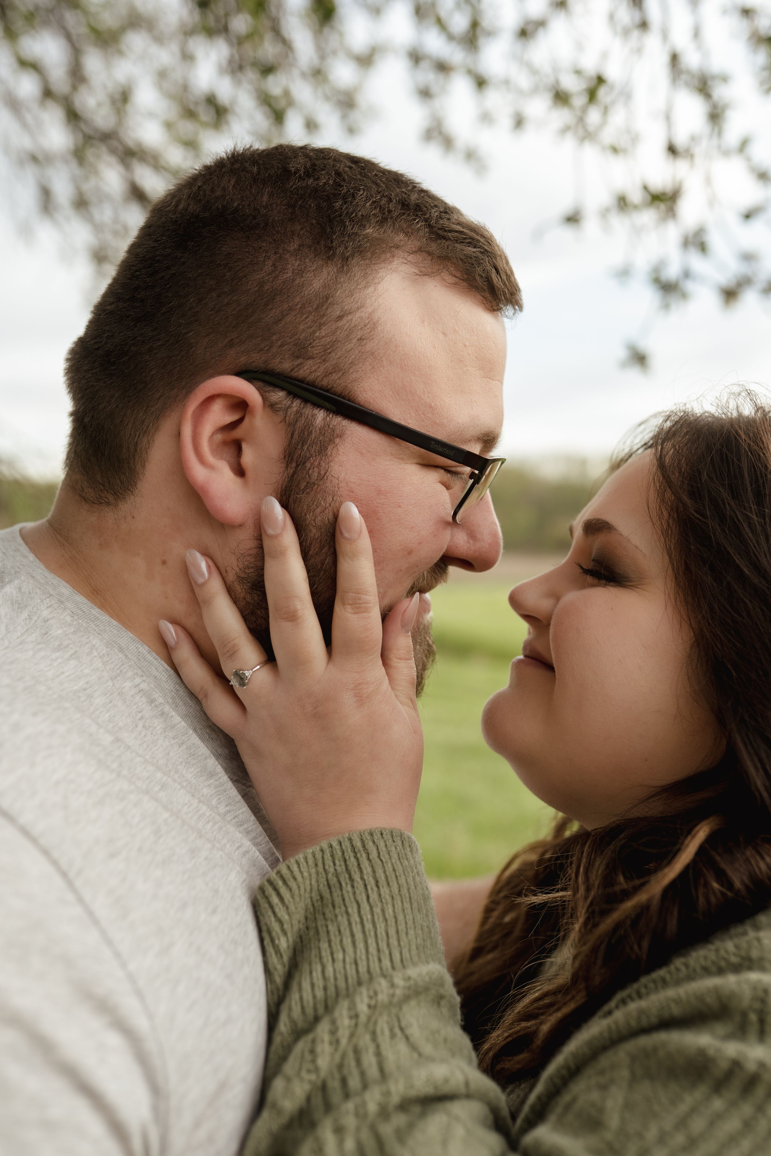 Two people lean in close together while sharing a tender moment in a natural outdoor setting.