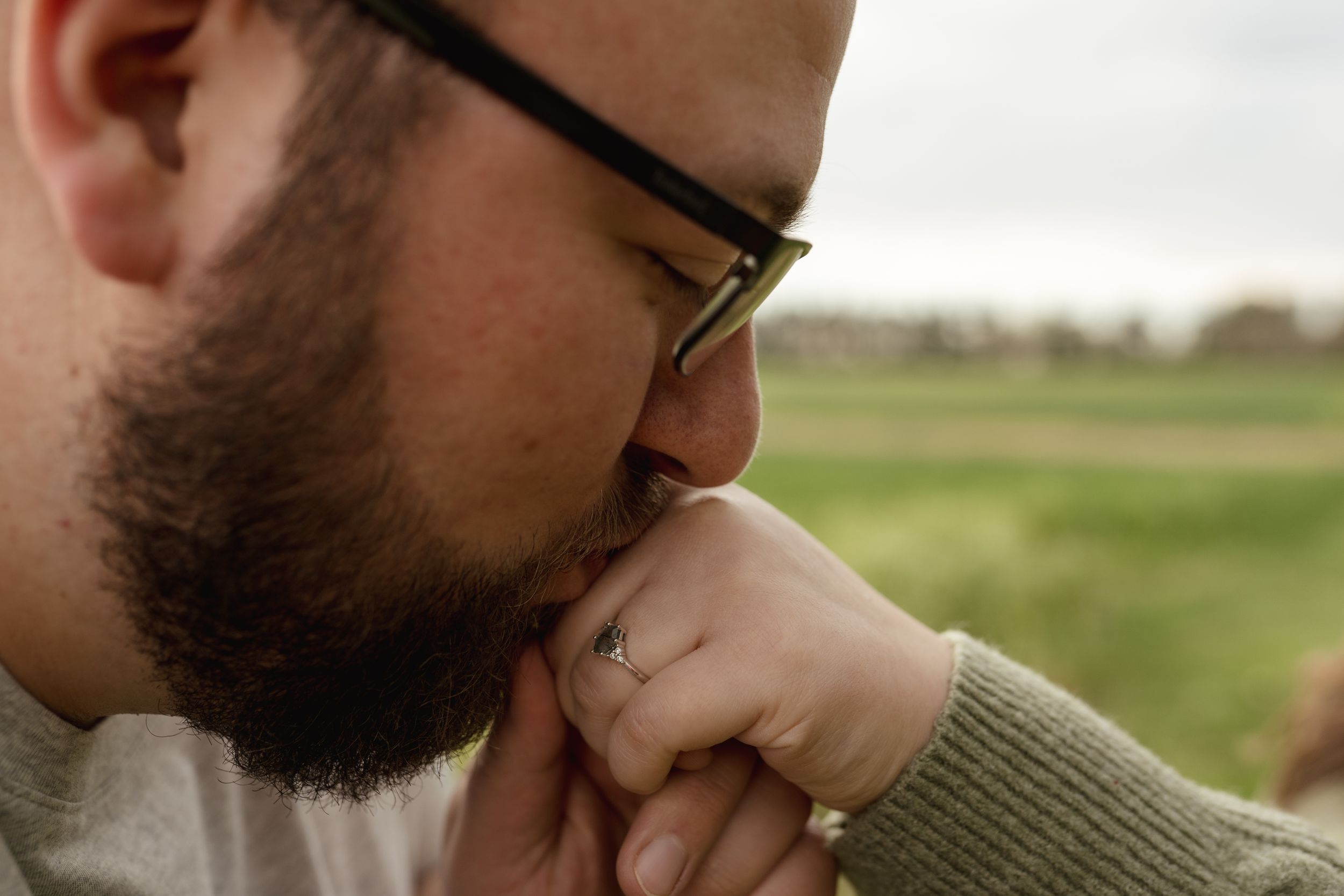Side profile view of a couple's faces close together in an intimate moment outdoors.