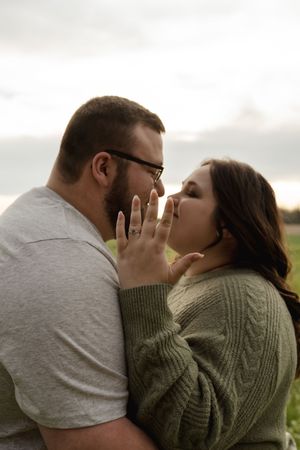 An affectionate couple embracing in a field wearing casual attire.
