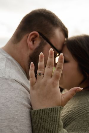 Close-up of hands with engagement ring during an intimate moment.