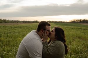 A couple shares tender moments in a scenic outdoor field.