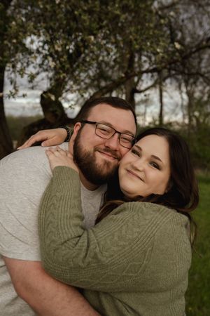 A couple shares a joyful embrace while sitting in a park setting.