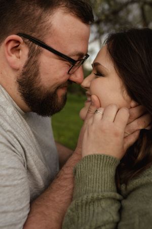 A romantic couple sharing an intimate close-up moment outdoors in natural lighting.
