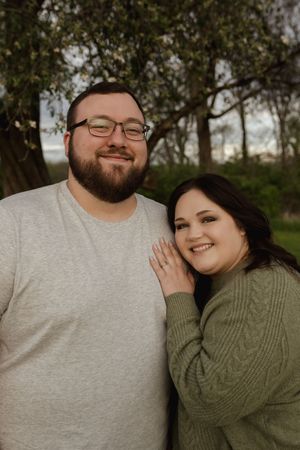 A couple in grey and olive sweaters sharing joyful laughter together outdoors.