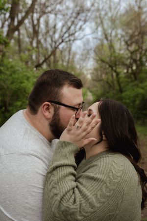 An intimate moment captured between a couple in casual sweaters outdoors.