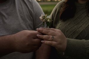 A couple shares an intimate moment exchanging rings in a romantic outdoor setting.