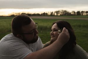 A couple shares an intimate moment under a tree during golden hour.