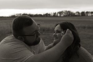 A romantic silhouette of a couple embracing in a field during sunset.