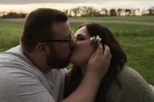 A couple embraces tenderly beneath a tree during a golden sunset.