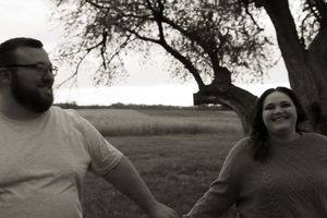 A black and white photo captures an intimate moment between two people under a tree.
