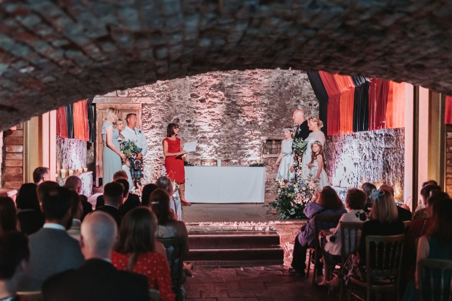 A performance takes place in a brick-arched venue with people watching from the audience in a dimly lit atmosphere.