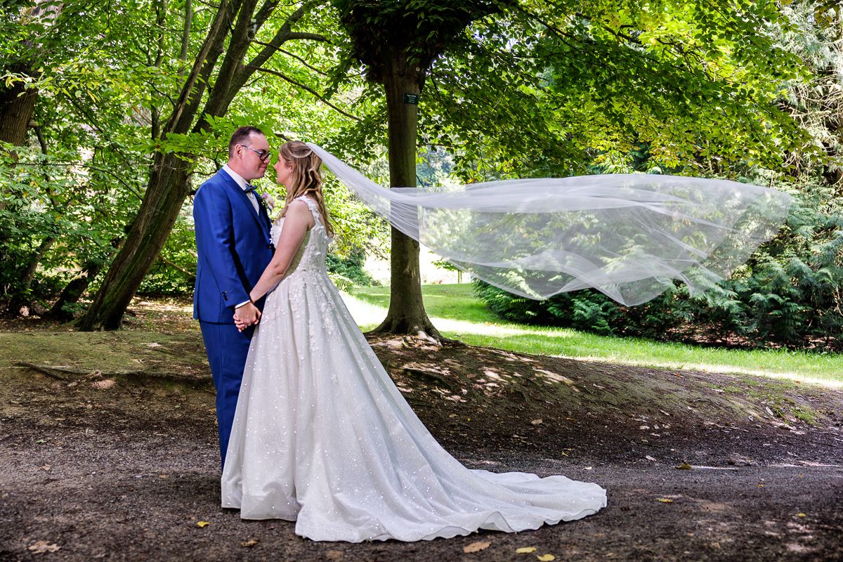 A tender embrace between newlyweds on a manicured lawn with brick wall background.
