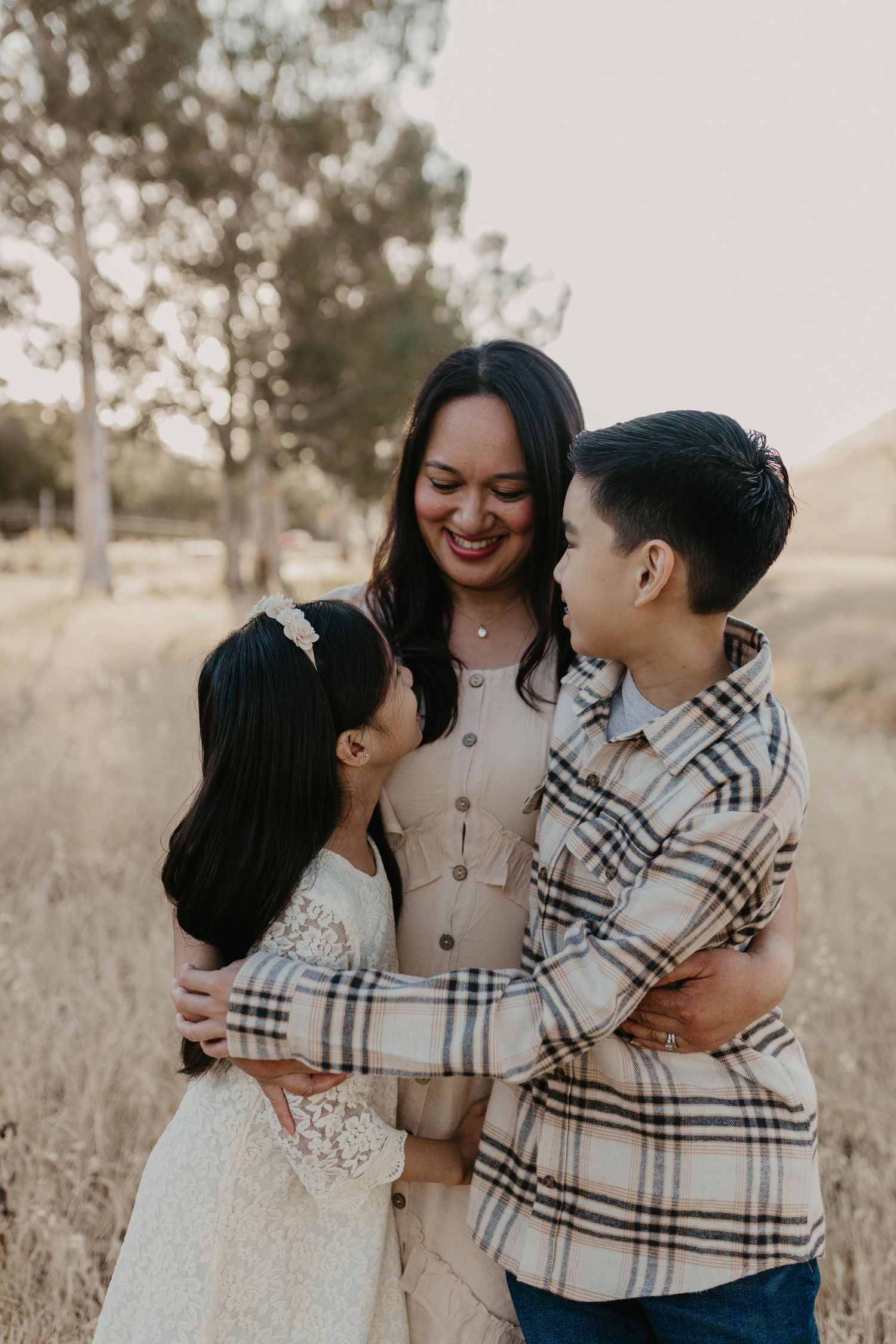 A tender family moment captured outdoors with coordinating plaid and neutral outfits.