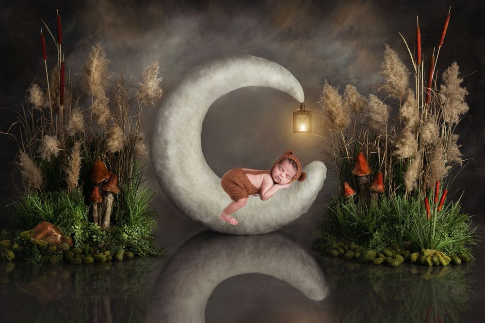 A dreamy nursery scene with a sleeping baby nestled in a glowing crescent moon surrounded by cattails and night foliage.
