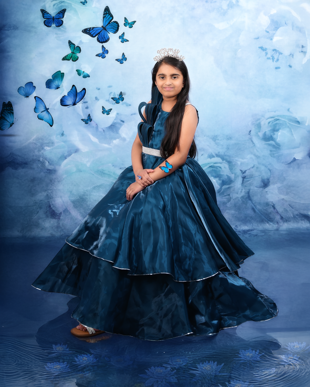 Fantasy portrait in a flowing navy blue ball gown with ethereal blue butterflies against a misty background.