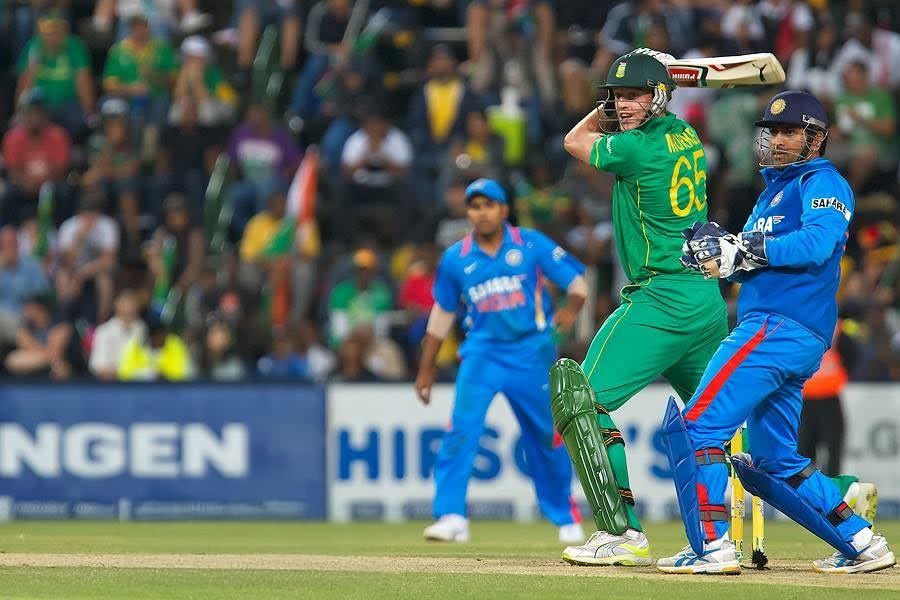 Cricket players in blue and green uniforms compete during an intense match on the field.
