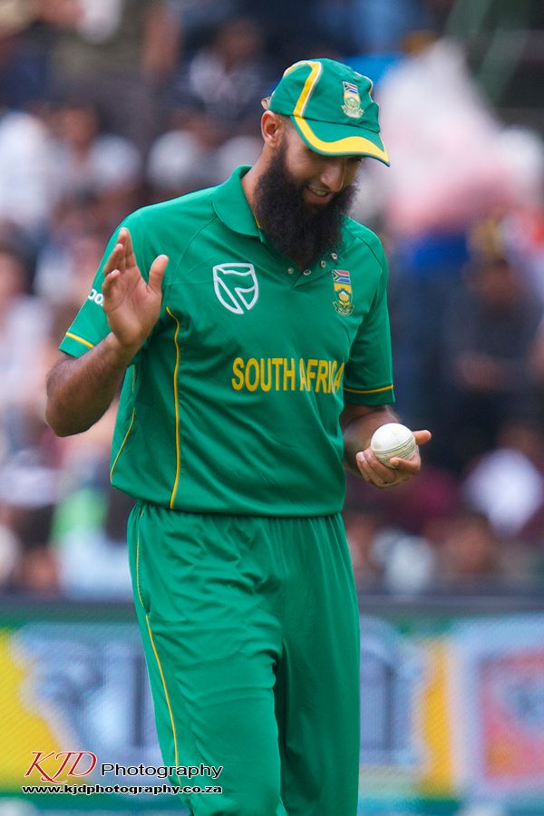 Cricket player in green South Africa uniform holding ball during match sequence shows bowling technique and delivery.