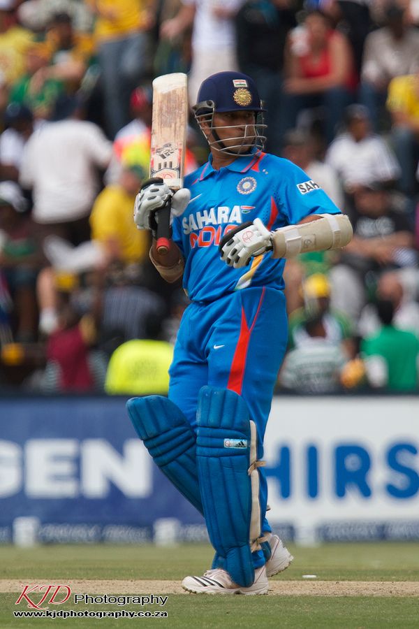 A cricket player in blue India jersey holding a bat on the field during a match.