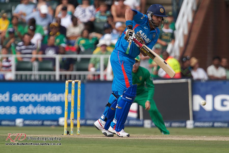 Cricket batsman in blue jersey plays an attacking shot during an international match against team in green.