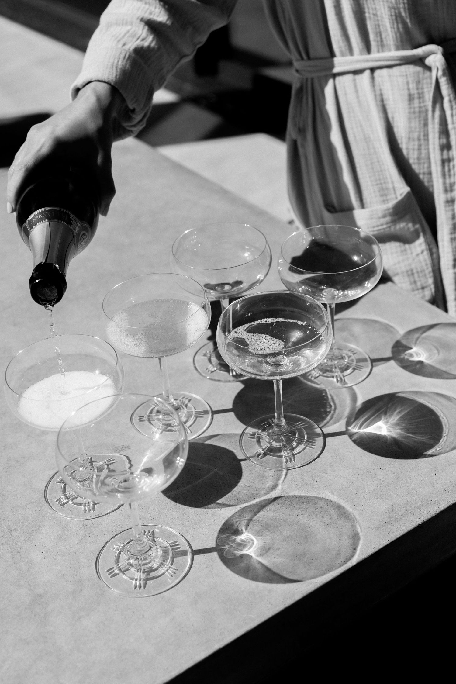 Black and white sequence showing wine glasses casting shadows on a white tablecloth during wine service.