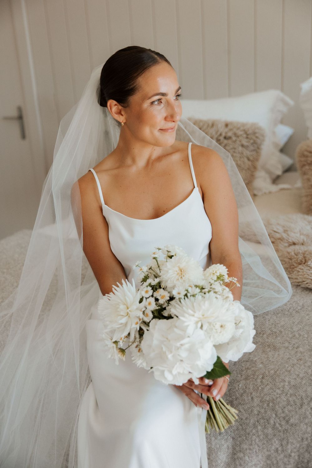 A bridal portrait featuring an elegant white slip dress and flowing veil.