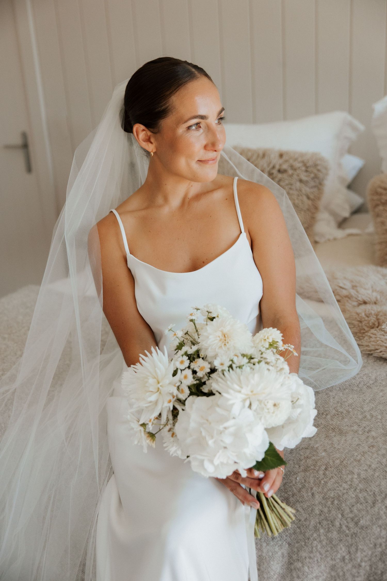 A bridal portrait featuring an elegant white slip dress and flowing veil.