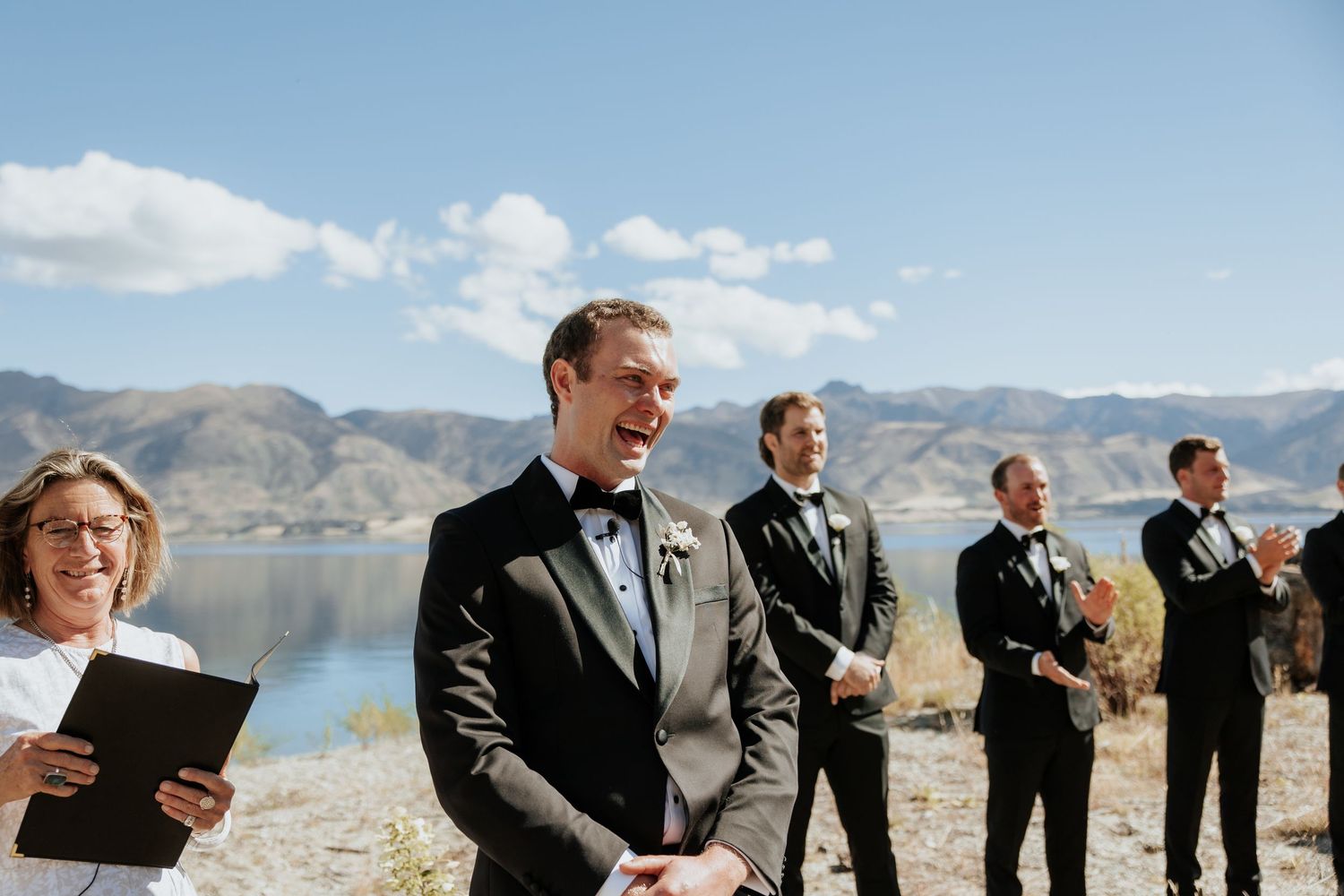A group stands at attention against a stunning mountain lake backdrop.