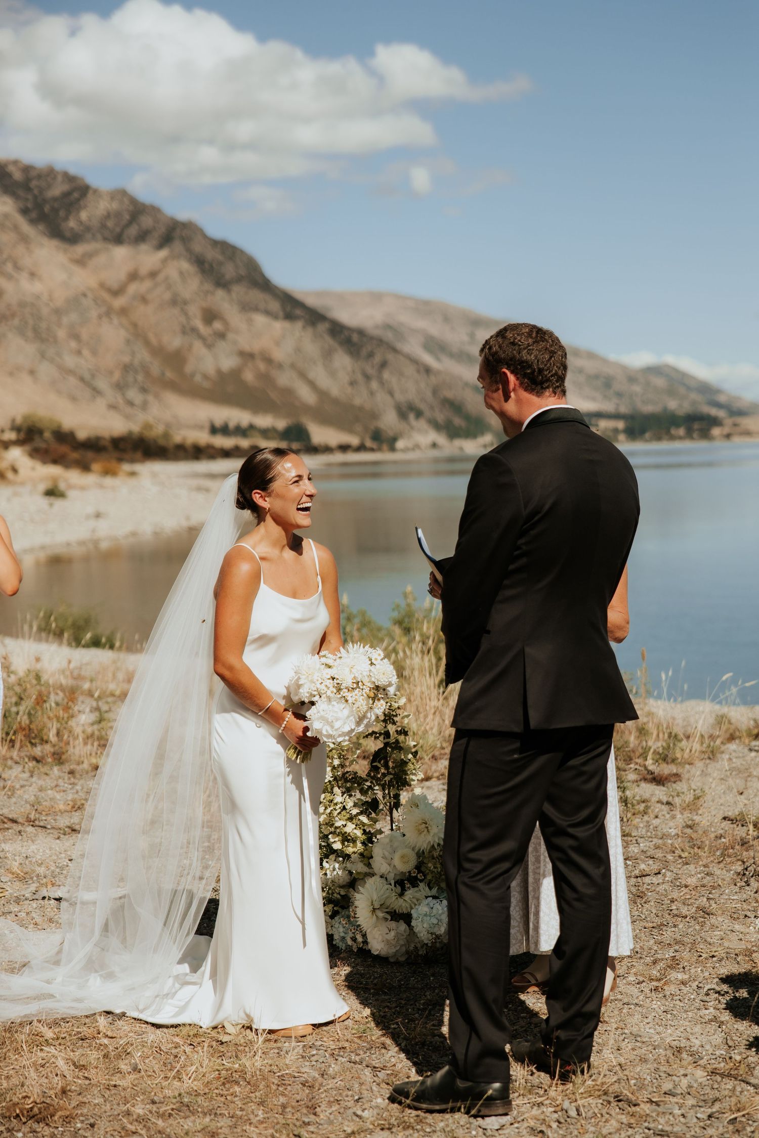 Joyful wedding ceremony taking place on a scenic mountain lakeside with dramatic landscape views.