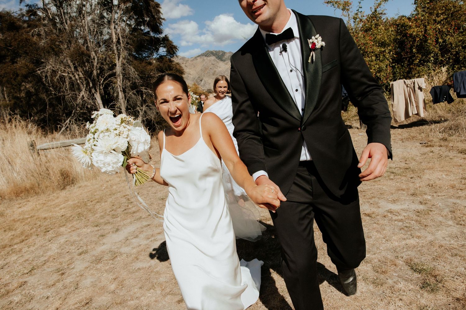 Newlyweds walking together and laughing during their outdoor mountain wedding.