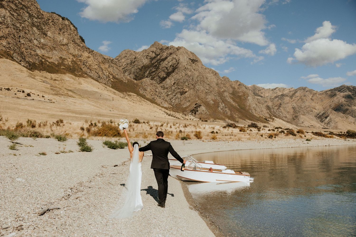 Panoramic view of a lakeside wedding celebration with desert mountains and blue skies.