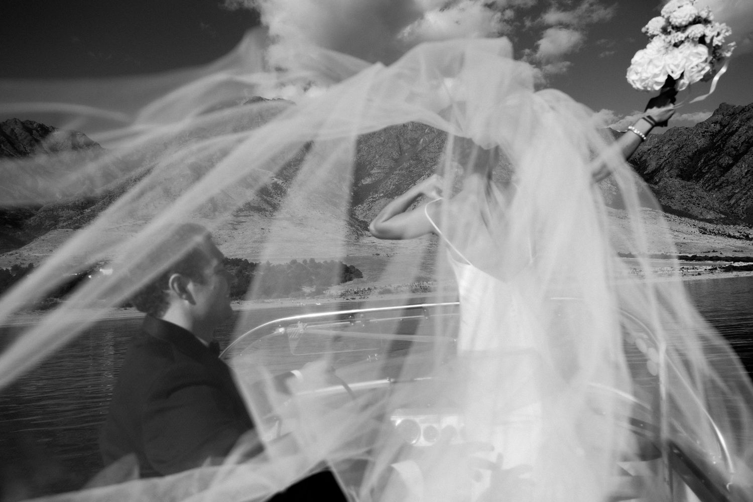 Artistic black and white photo of a couple through a flowing wedding veil.