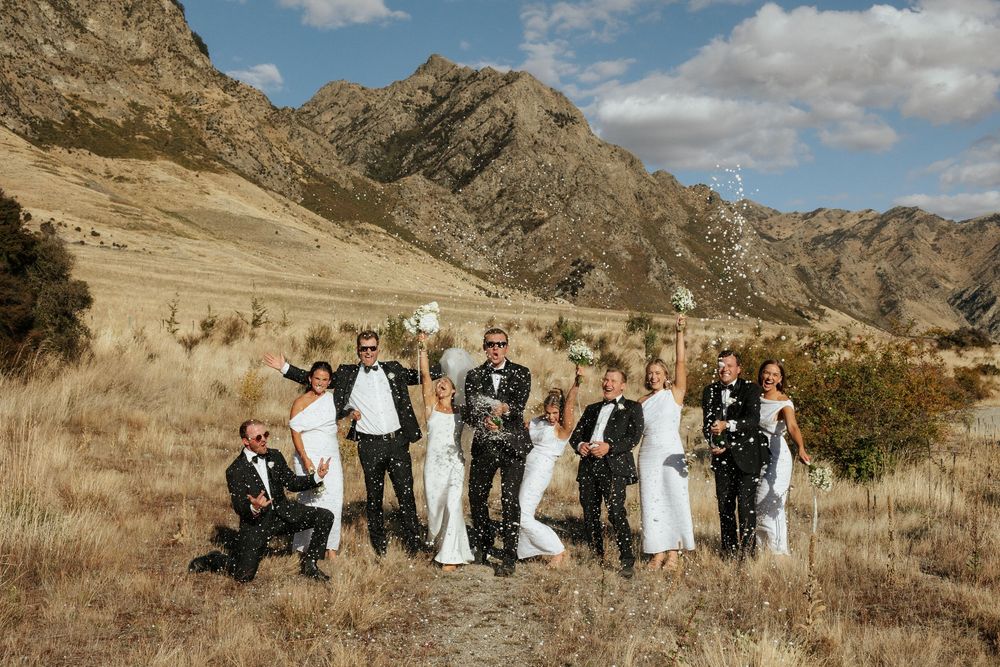 Wedding party group photo with mountains and golden grass landscape in background.