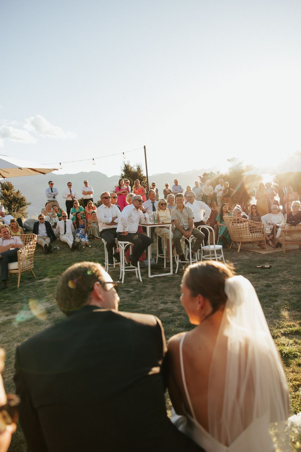 Outdoor wedding reception with mountain backdrop and string lights at golden hour.