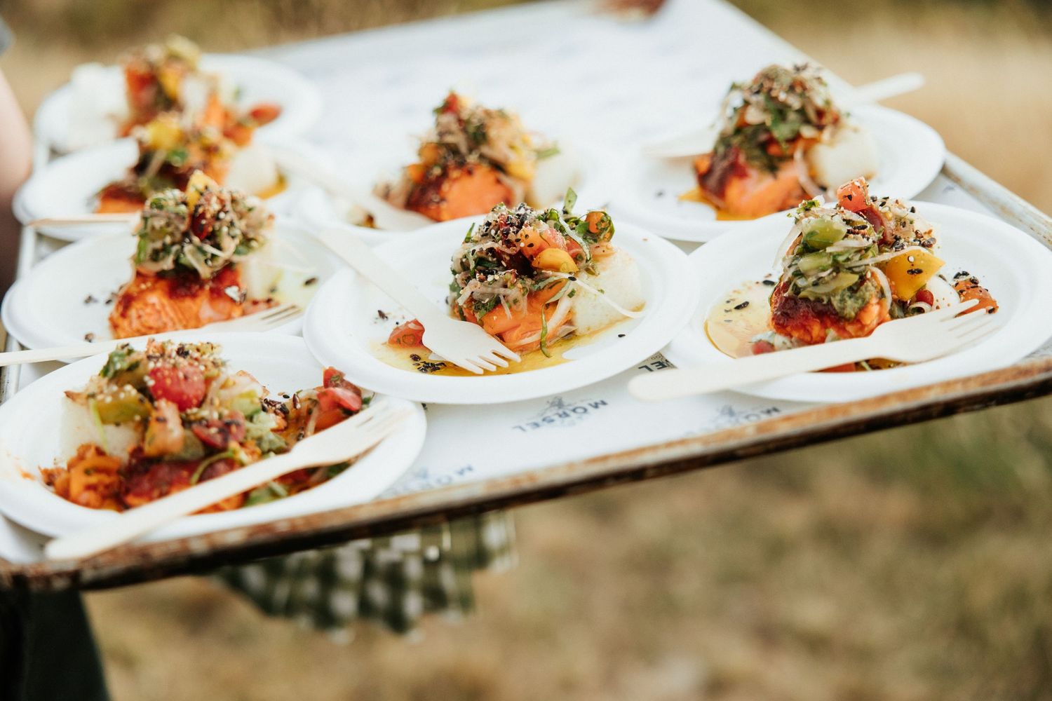 Plated appetizers on white dishes arranged on serving tray with colorful garnishes.
