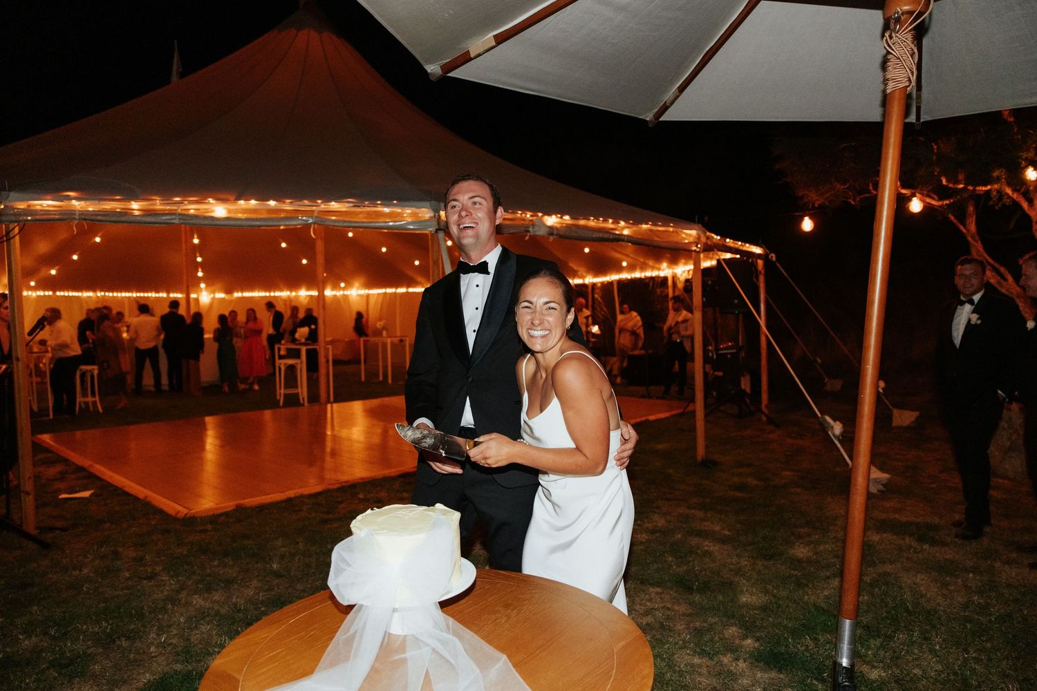 Wedding reception at night under illuminated tents with warm lighting creating a romantic ambiance.