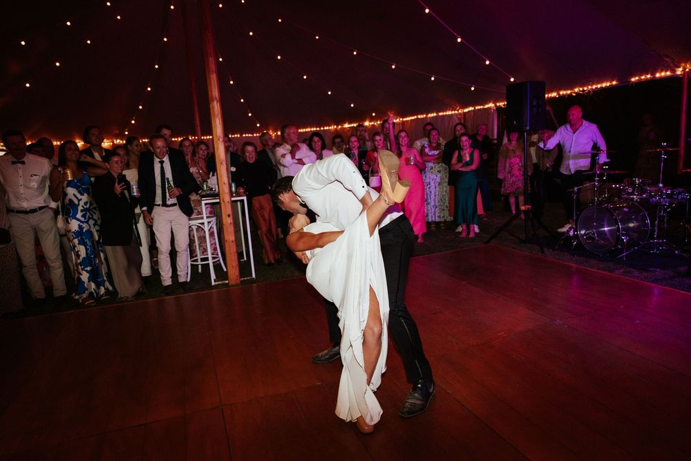 First dance moment under string lights in reception tent.