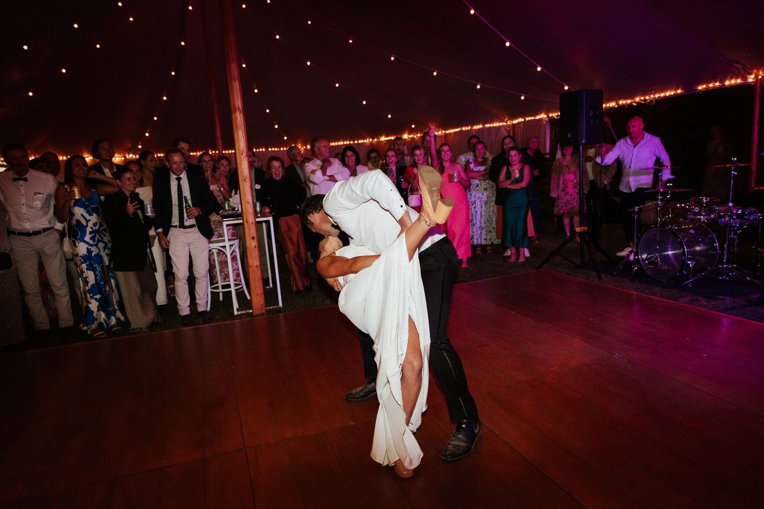 First dance moment under string lights in reception tent.