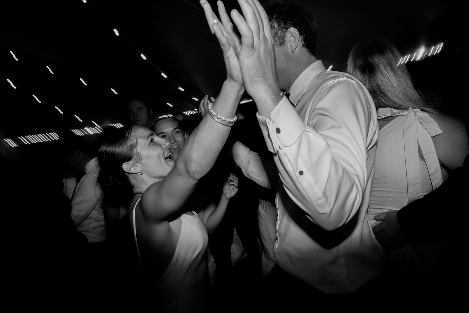 Wedding guests dance enthusiastically on a dark dance floor with motion blur effects.