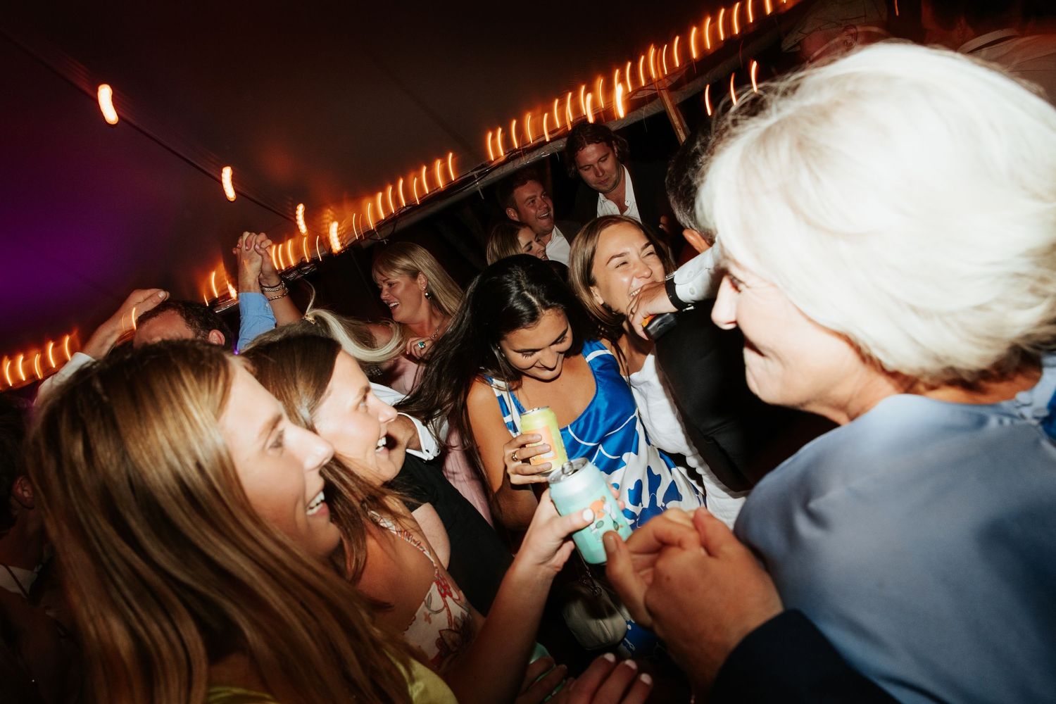 Partygoers dancing and celebrating on a crowded dance floor under club lighting.