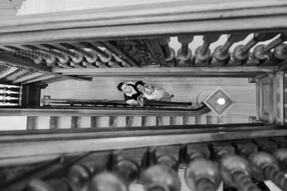 Black and white aerial view of a couple embracing on an ornate staircase with decorative balusters.