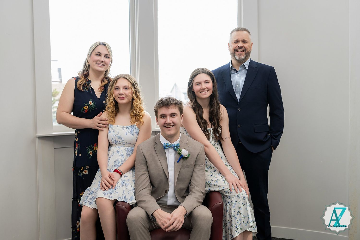 Wedding party poses together in a modern indoor setting with white walls and natural lighting.