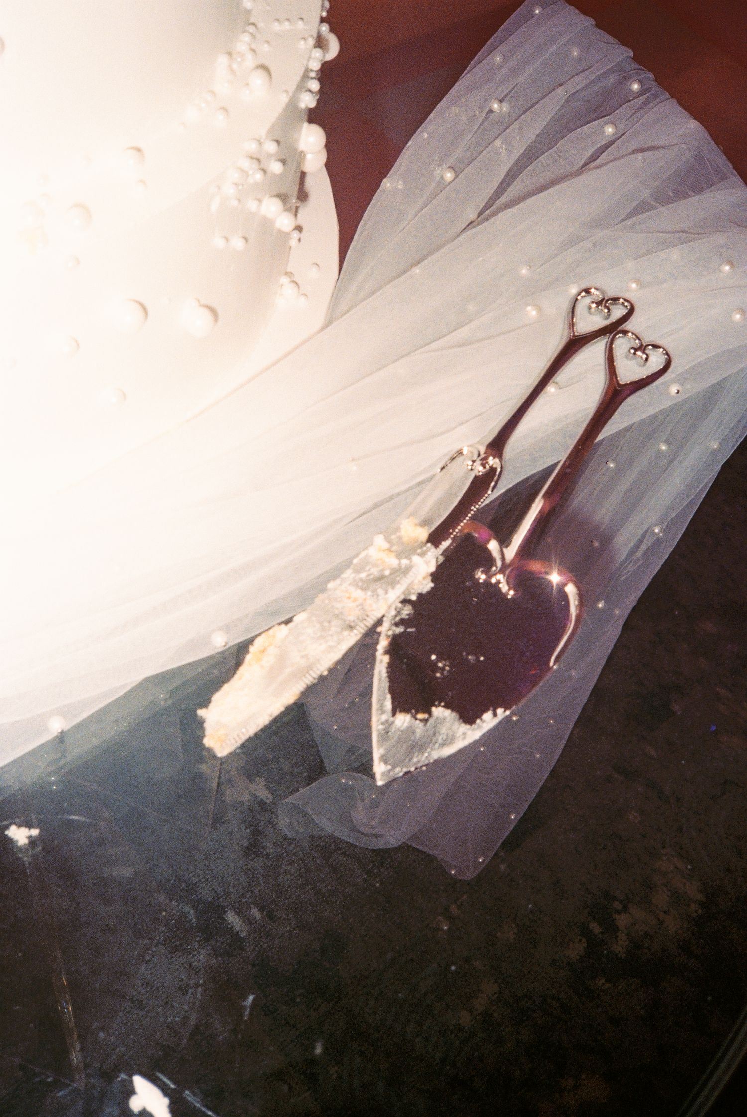 Delicate wedding shoes rest on flowing white tulle veil with romantic lighting.