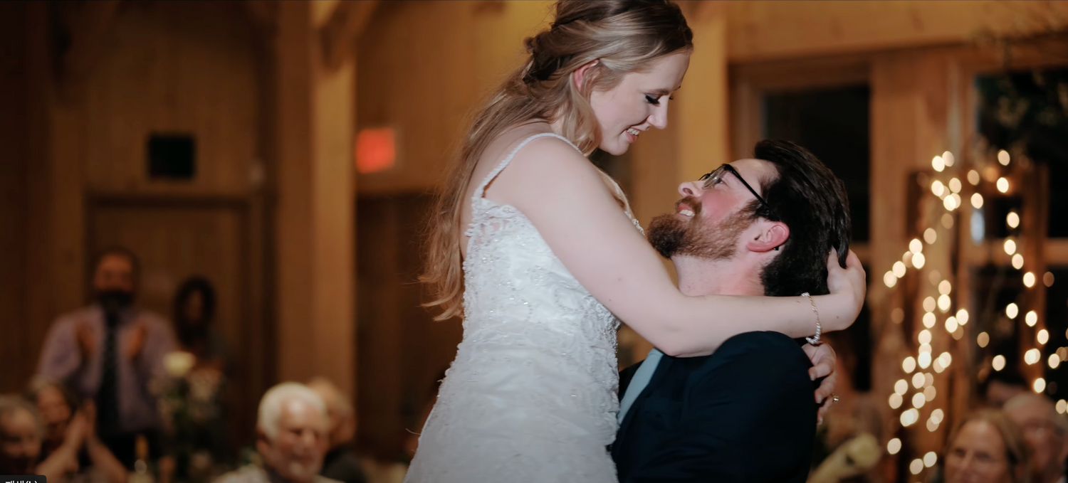 Couple shares intimate first dance under warm lighting at indoor wedding reception.