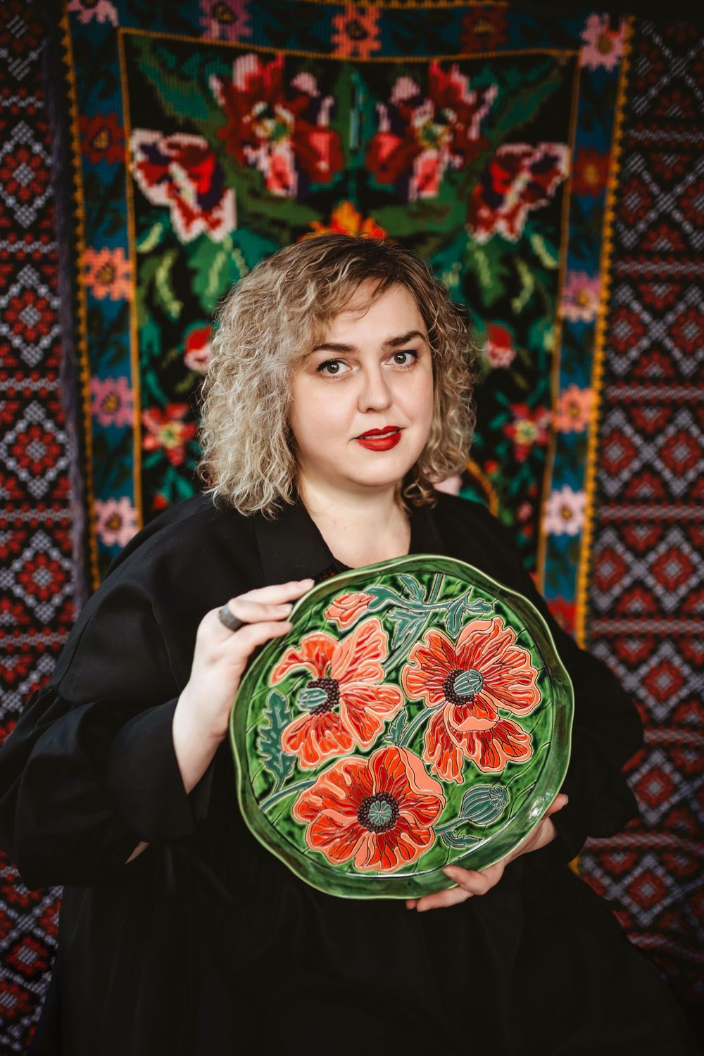 Series of photos showing someone posing with a decorative green ceramic plate featuring striking orange floral designs.